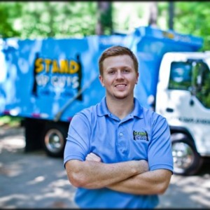 casey walsh, owner of stand up guys junk removal in from of a dump truck