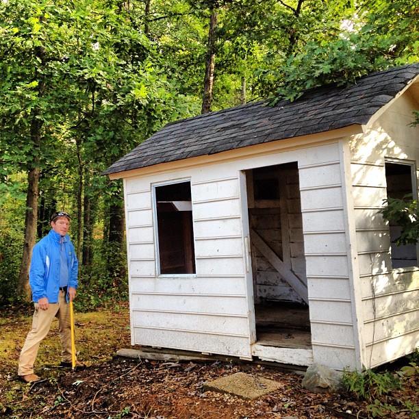 man standing next to junk shed