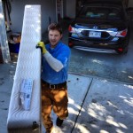 man carrying a junk mattress